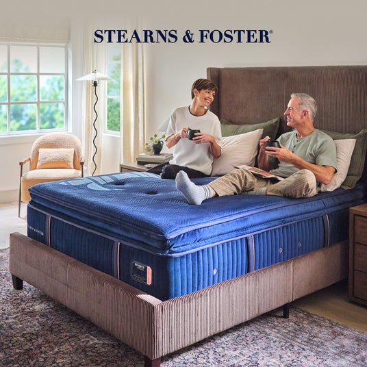 Couple enjoying a Stearns & Foster mattress drinking coffee in a bedroom