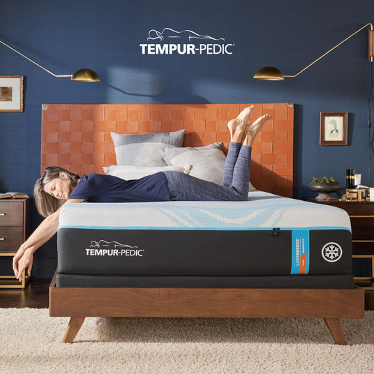 A women laying across the Tempur-Pedic Mattress looking at the bedroom floor