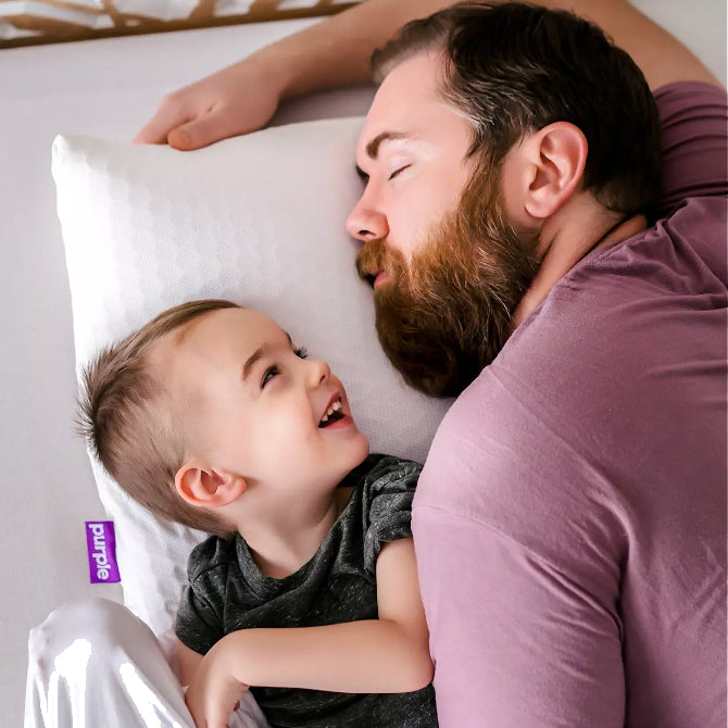 Dad and son sleeping on purple mattress and pillow