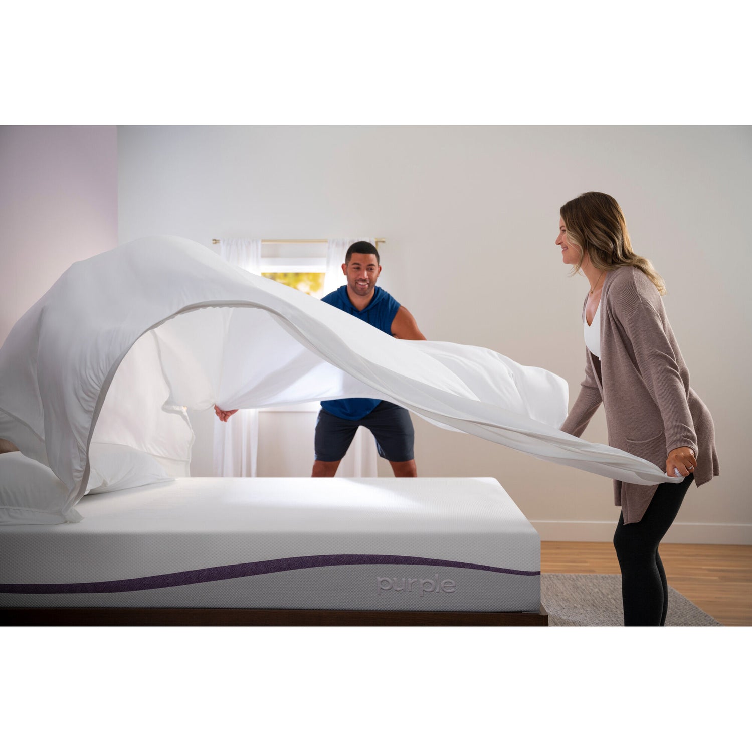 Couple puttng bedding on The Purple Mattress