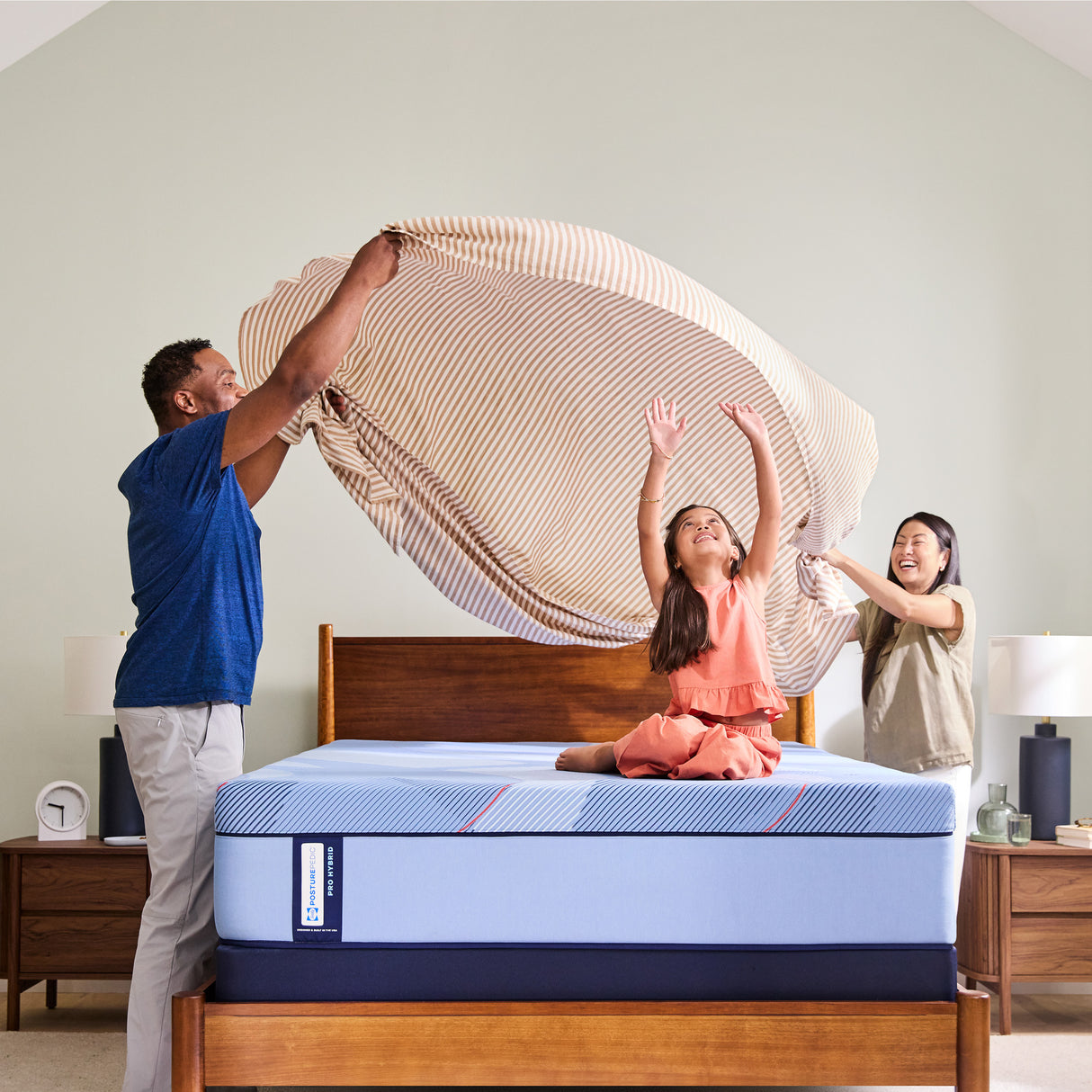Family setting with a child playing on a mattress in a bedroom.