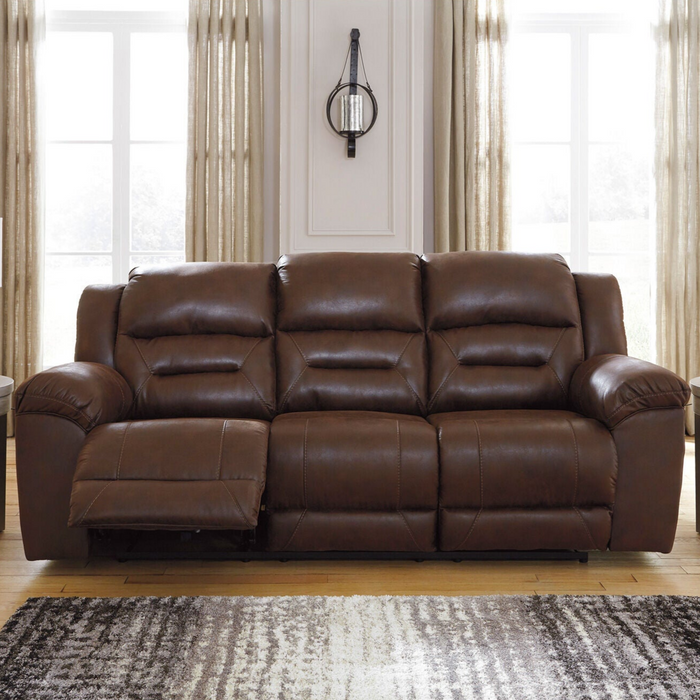 Brown leather sofa in a living room with large windows and curtains.