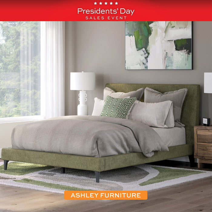 Bedroom with a green bed and gray bedding, featuring Ashley Furniture branding and Presidents' Day sales event text.
