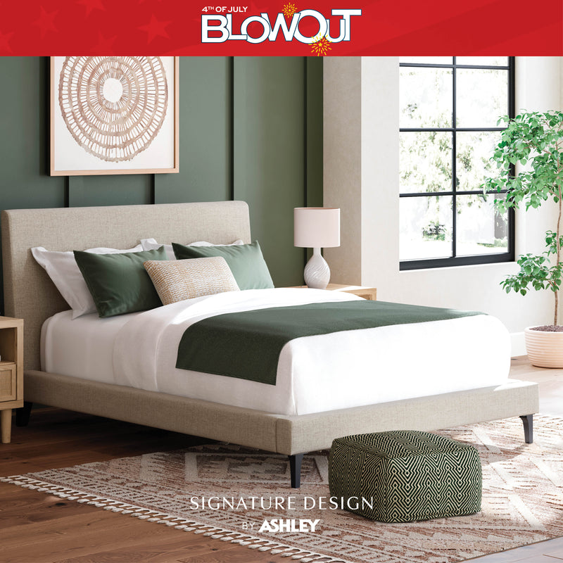 Bedroom with a bed and ottoman, featuring Ashley furniture branding.