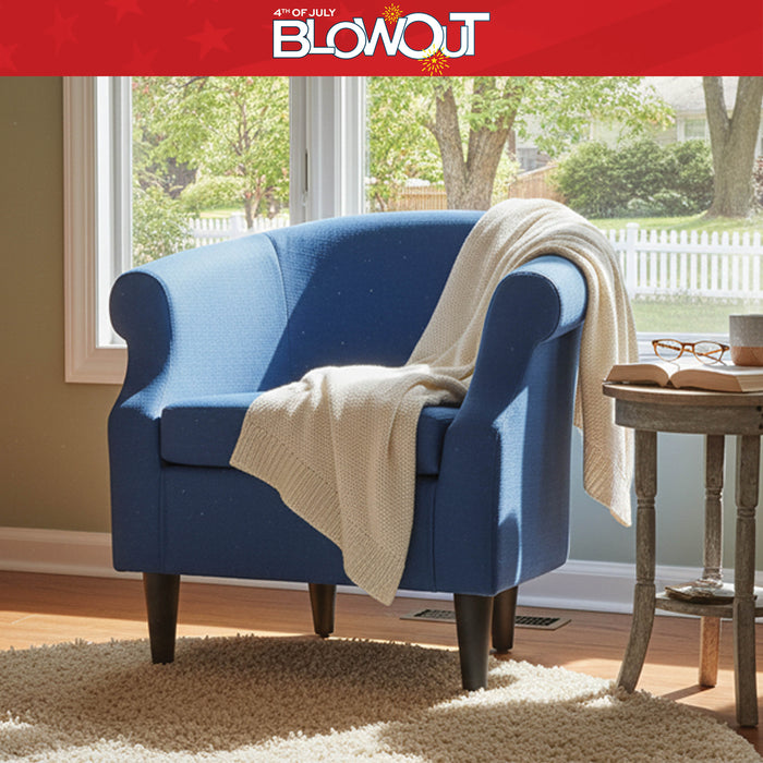 Blue armchair with a beige blanket in a room with a window view of trees and a white picket fence.