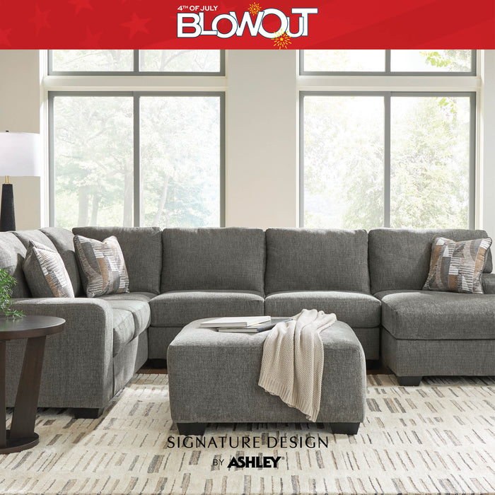 Gray sectional sofa in a living room with '4th of July Blowout' and 'Signature Design by Ashley' text.