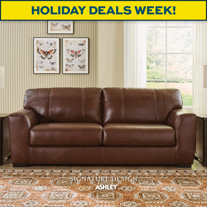 Brown leather sofa in a living room with 'Holiday Deals Week!' banner and Signature Design by Ashley logo.