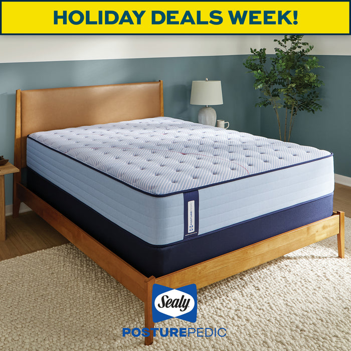 Blue mattress on a wooden bed frame with 'Sealy Posturepedic' branding and 'Holiday Deals Week!' text.