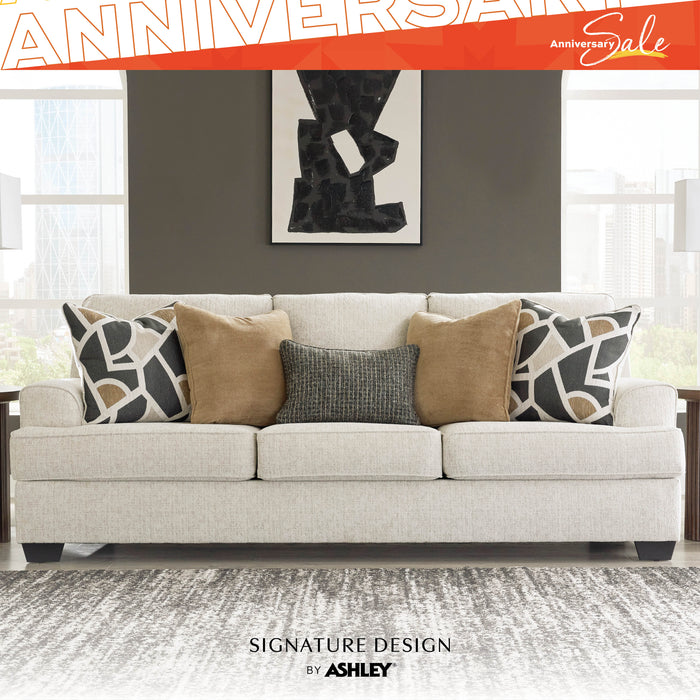 Gray sofa with patterned pillows in a living room setting, featuring 'Signature Design by Ashley' branding.