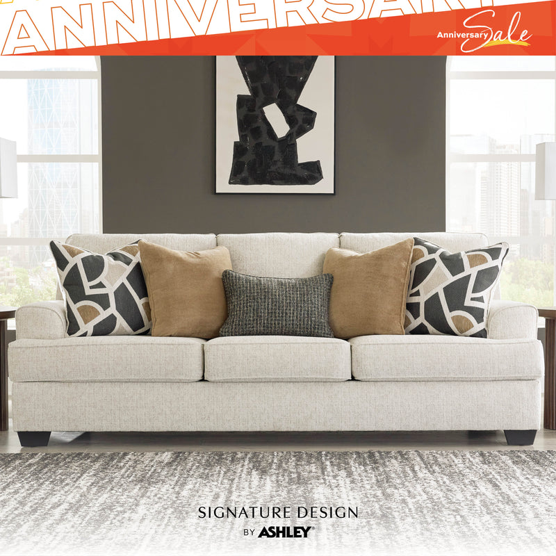 Gray sofa with patterned pillows in a living room setting, featuring 'Signature Design by Ashley' branding.
