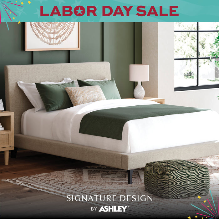 Bedroom with a bed and nightstands, featuring 'Signature Design by Ashley' branding and Labor Day sale text.