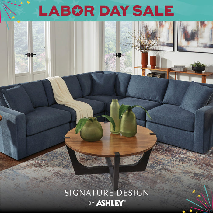 Blue sectional sofa in a living room with a coffee table and decor, featuring Ashley Furniture branding.