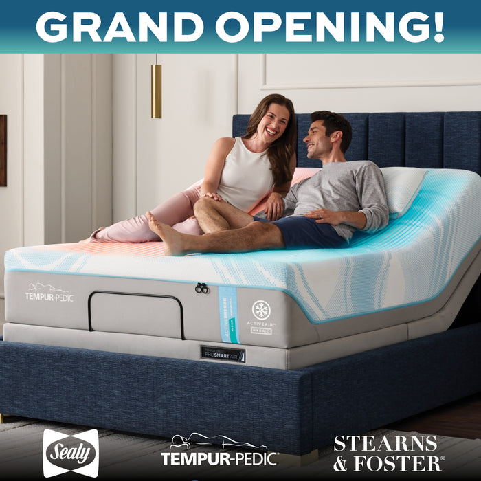 Couple sitting on a Tempur-Pedic mattress with 'Grand Opening!' text above.