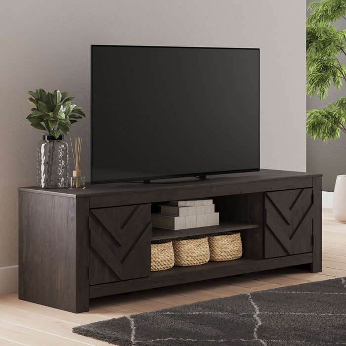 Dark wood TV stand with a television on top in a room with plants and a rug.