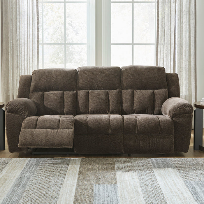 Brown reclining sofa in a living room with side tables and lamps.