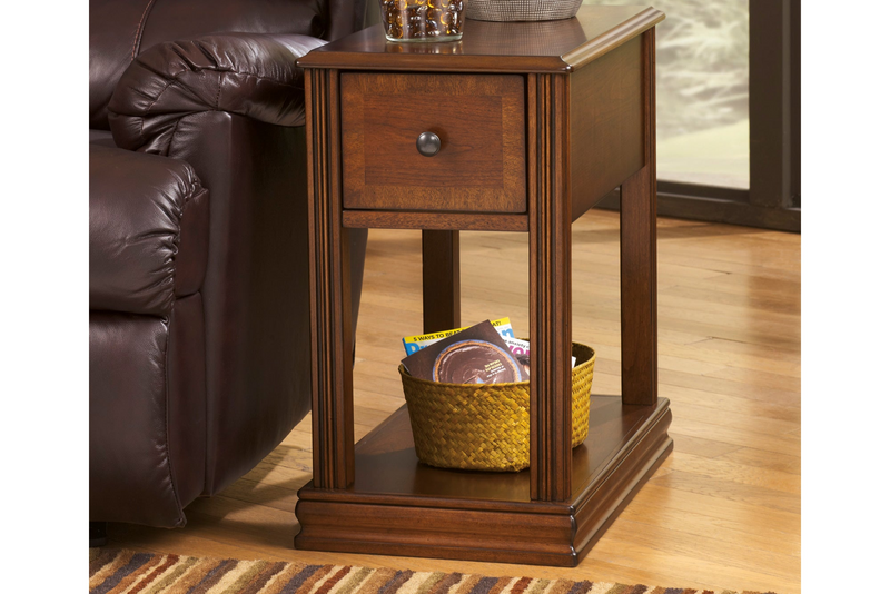 Wooden side table with a basket on a wooden floor next to a brown leather couch.