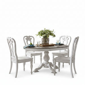 A white distressed round dining table with four matching high-back chairs, styled with a green floral centerpiece and place settings on a clean white background.