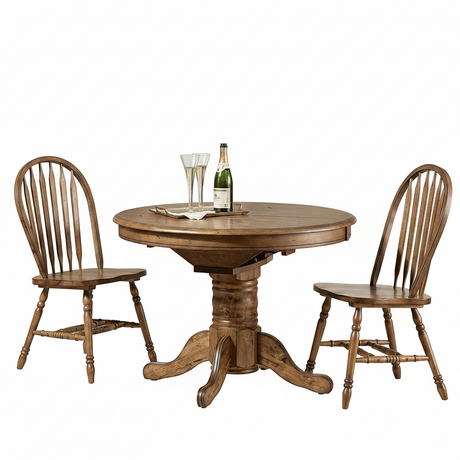 A round wooden pedestal dining table with two matching spindle-back chairs, shown on a clean white background. The table is set with two champagne flutes and a bottle.