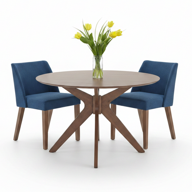 A round dining table with a light brown wood-grain top and X-shaped wooden legs, accompanied by two blue upholstered chairs. A clear glass vase filled with yellow tulips sits in the center of the table on a clean white background.