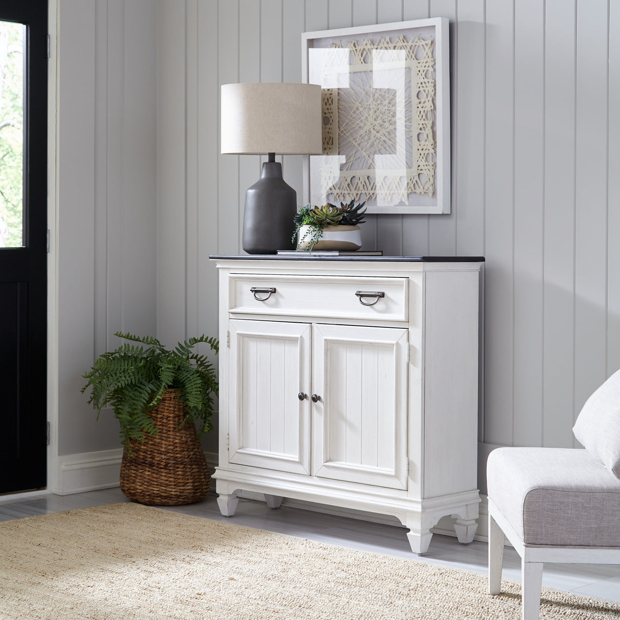 White cabinet with decorative items in a room with gray walls and a rug.
