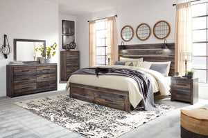 A rustic dark wood bedroom furniture set including a bed frame, headboard, dresser, chest, and nightstand, styled in a bright modern bedroom with beige curtains, a patterned rug, and neutral bedding.