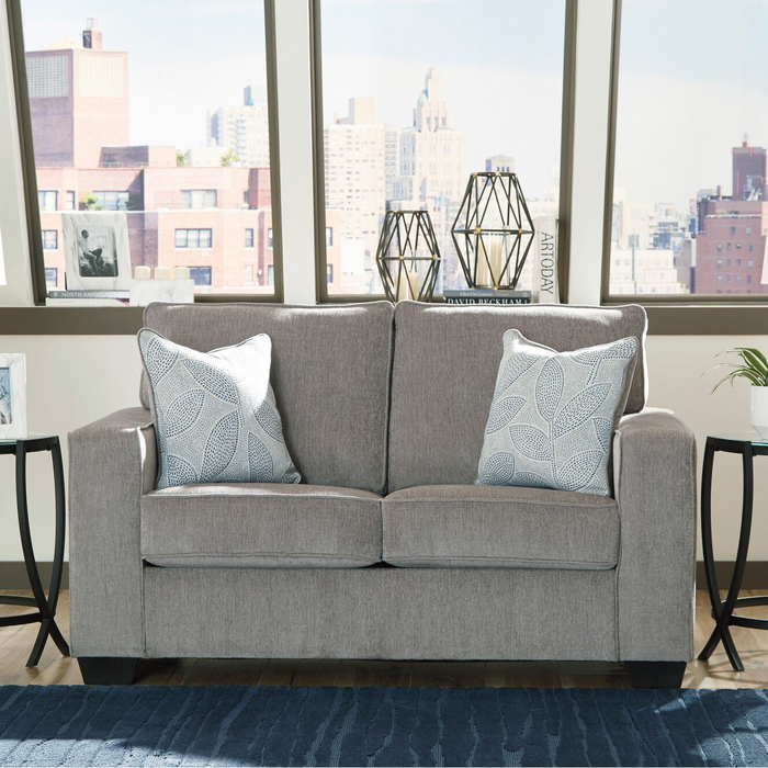 Gray apartment sofa with decorative pillows in a room with large windows showing a cityscape.