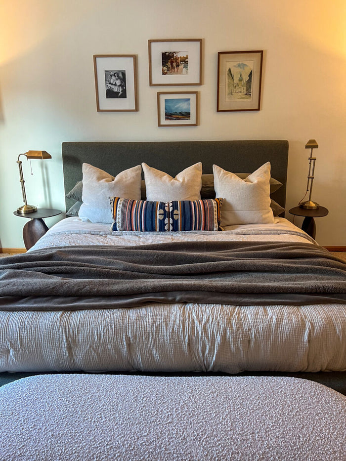 Bedroom with a neatly made bed, decorative pillows, and framed pictures on the wall.